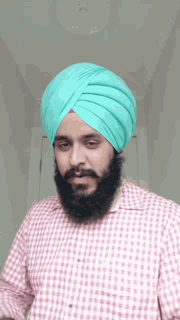 a man with a beard and a turban is wearing a pink and white checkered shirt