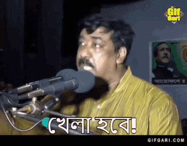a man with a mustache is speaking into a microphone and says " gifgari.com " on the bottom