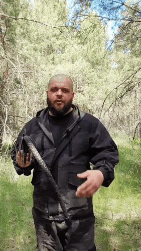 a man in a black jacket is holding a snake in his hand