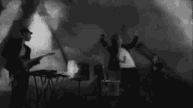 a black and white photo of a band playing instruments on stage .