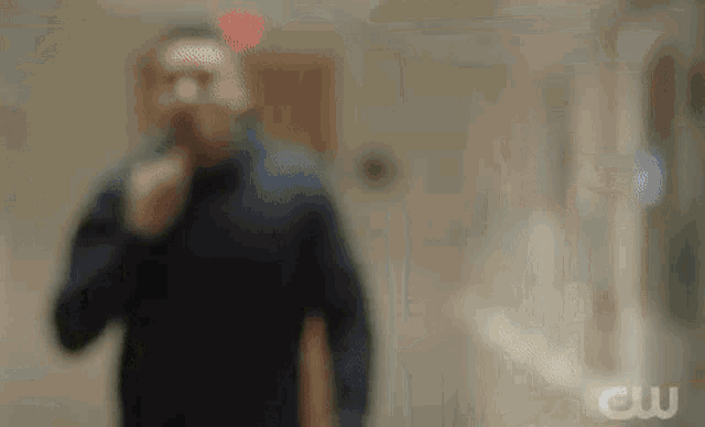 a blurry picture of a man walking down a hallway with a cigarette in his mouth .