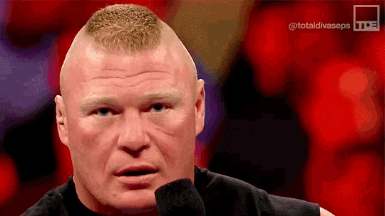 a close up of a man 's face with a shaved head talking into a microphone .