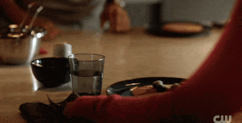 a glass of water sits on a table next to a bowl