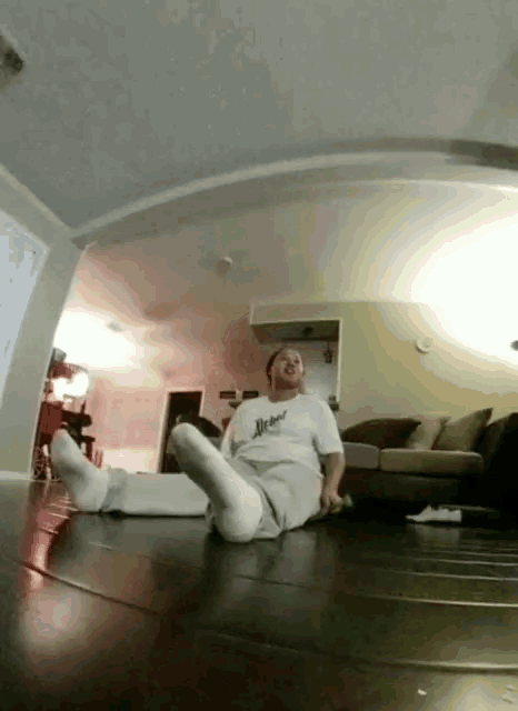 a man is laying on the floor in a living room wearing a shirt that says ' dead '