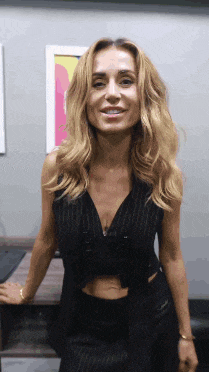 a woman with blonde hair wearing a black vest and skirt