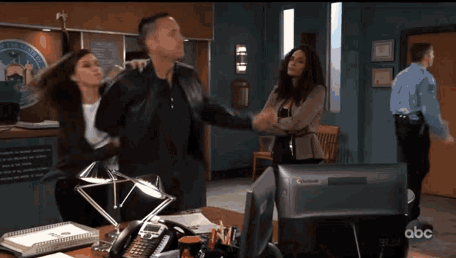 a man and a woman are fighting in a police station while a police officer watches