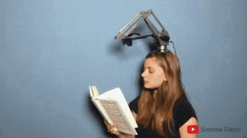 a woman is reading a book while wearing headphones and a robotic arm on her head