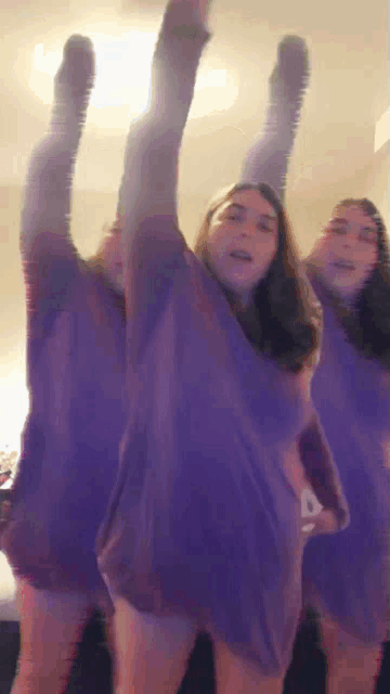 three women in purple shirts are dancing together