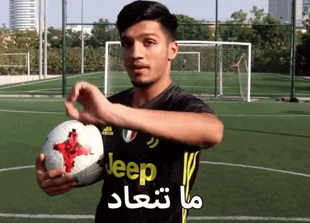a young man wearing a black jeep jersey holds a soccer ball