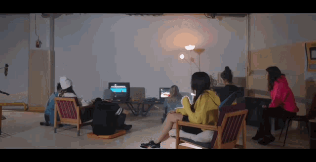 a group of people are sitting in chairs watching television