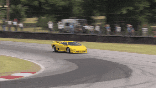 a yellow sports car is driving down a track