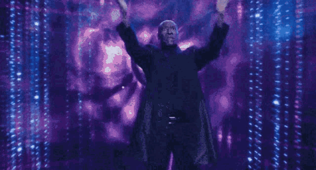 a man in a black jacket is standing in front of a blue and purple background .