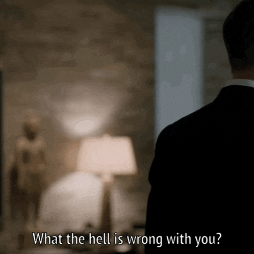 a man in a suit stands in a room and says what the hell is wrong with you