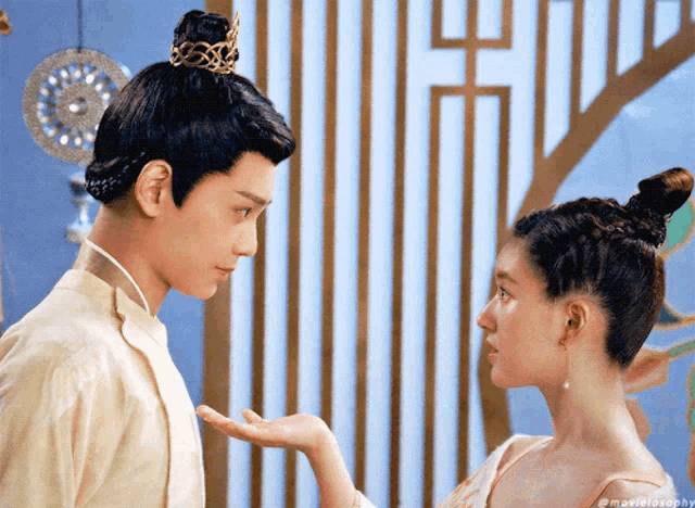 a man and a woman are looking at each other and the woman is wearing a bun