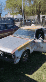 a white car with a yellow stripe on the side is parked in the grass