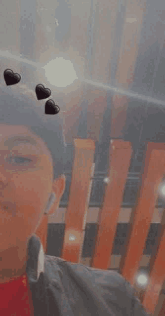 a young man is taking a picture of himself with hearts on his head .