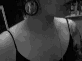 a black and white photo of a woman wearing a black tank top and earrings