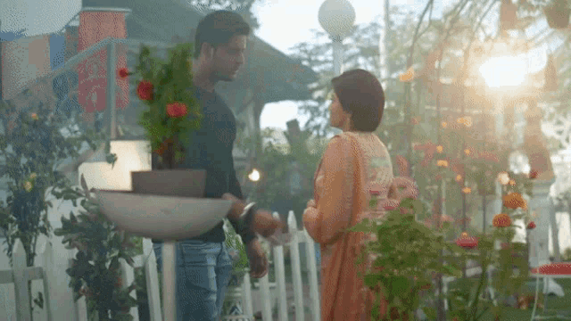 a man and woman are standing next to each other in front of a white fence