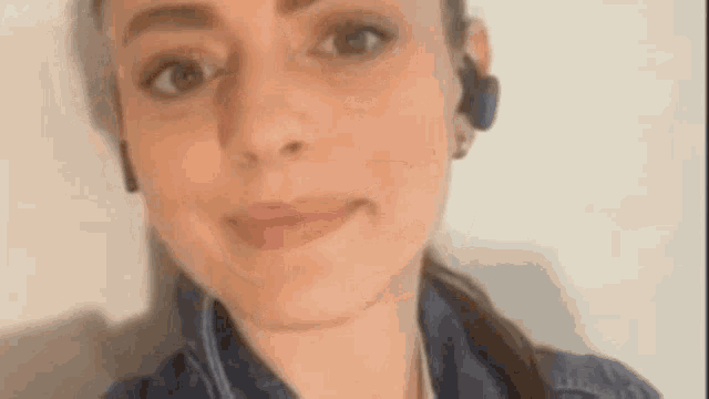 a woman wearing headphones and a blue jacket is smiling .