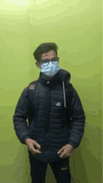 a young man wearing a face mask and glasses .