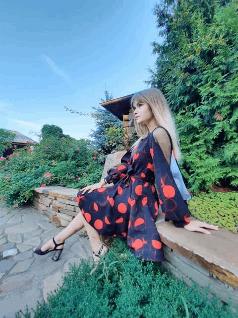 a woman in a dress sits on a stone wall
