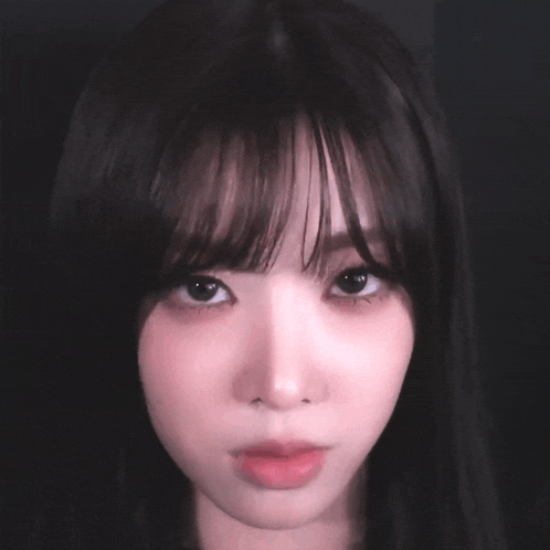 a close up of a woman 's face with dark hair and bangs