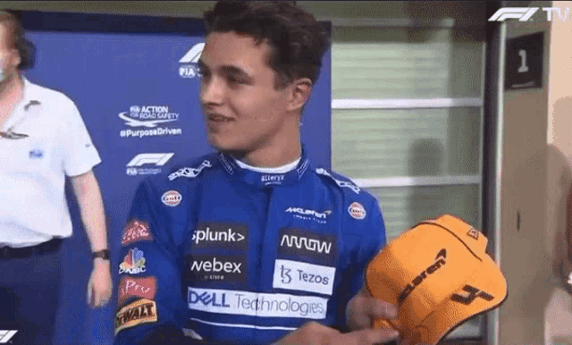 a man in a mclaren shirt is holding a hat with the number 4 on it