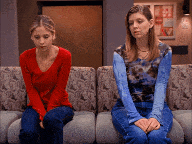 a woman in a red shirt sits next to another woman in a blue tie dye shirt