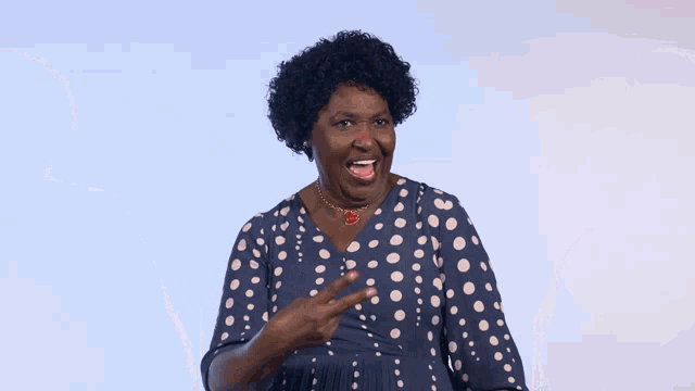 a woman in a polka dot dress is smiling and giving the peace sign