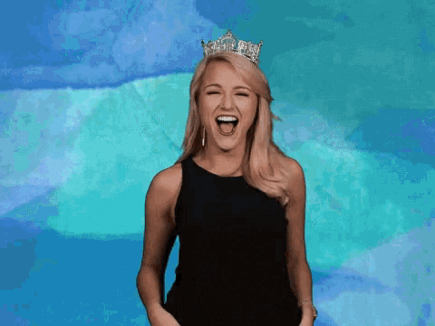 a woman wearing a tiara is laughing with her mouth wide open
