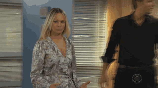 a woman in a ruffled top stands next to a man
