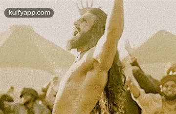 a shirtless man with a beard and long hair is standing in front of a crowd .
