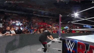 a wrestling match is taking place in a stadium with a crowd watching .