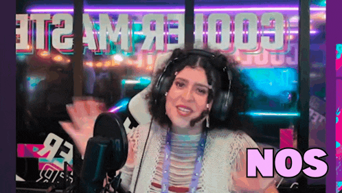 a woman wearing headphones is standing in front of a microphone and says nos .