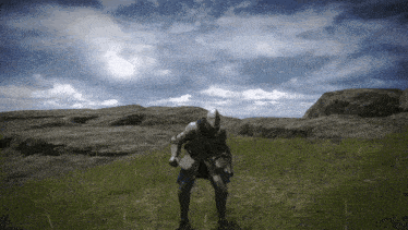 a man in a knight 's armor is standing in a grassy field