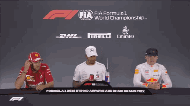 three men are sitting at a table in front of a sign for the fia formula 1 world championship