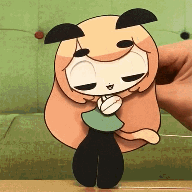 a hand is holding a cartoon character with a green shirt on