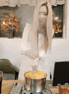 a woman in a white dress stirs a pot of food
