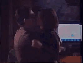 a man and woman are kissing in front of a tv
