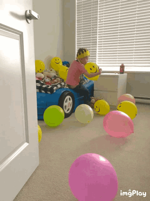 a little girl is playing with balloons in a room with imagesplay on the bottom right