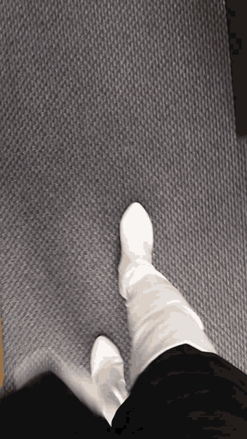 a person wearing white boots is standing on a grey carpet