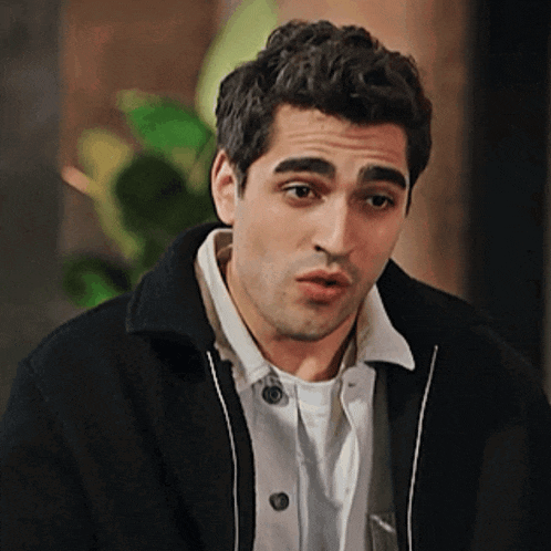a man wearing a black jacket and a white shirt is making a face