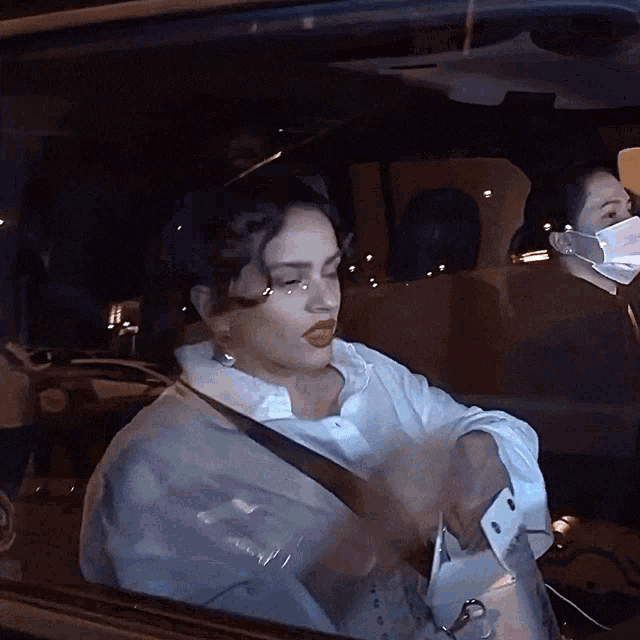 a woman wearing a mask sits in a car at night