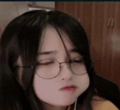 a close up of a girl wearing glasses and making a funny face .