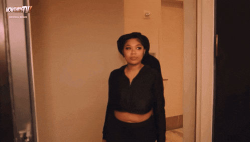 a woman is standing in a hallway with a sign that says nowthis tv