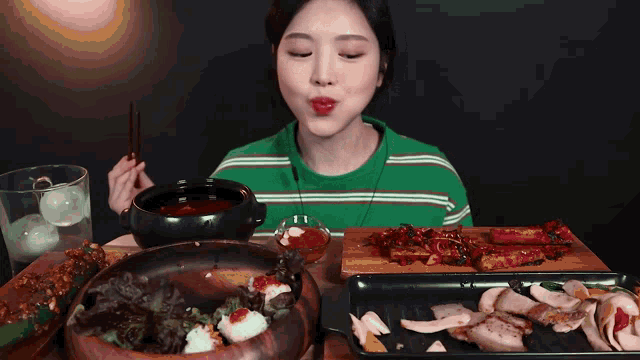 a woman in a green and white striped shirt is eating food