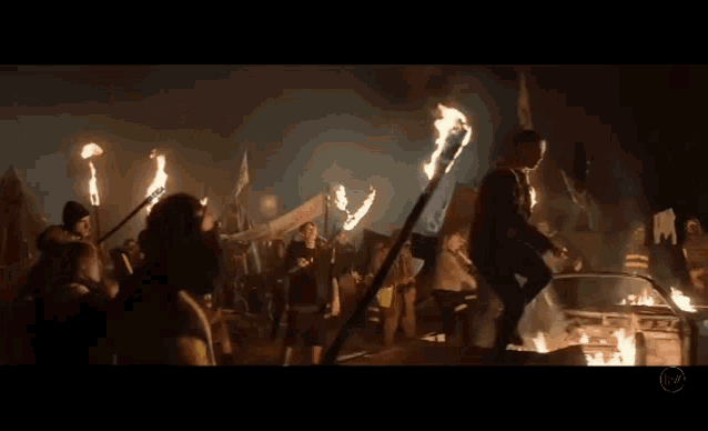 a man is standing in front of a crowd of people surrounded by flames .