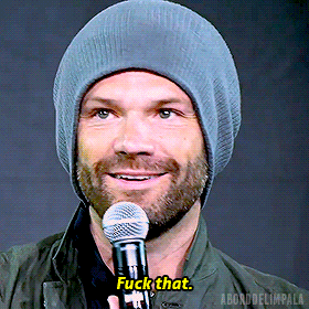 a man wearing a beanie is holding a microphone and saying fuck that