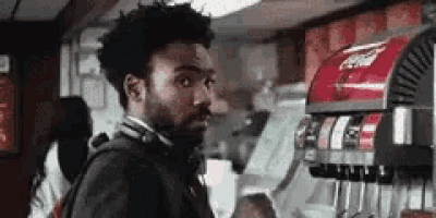 a man is standing in front of a coca cola machine in a restaurant .