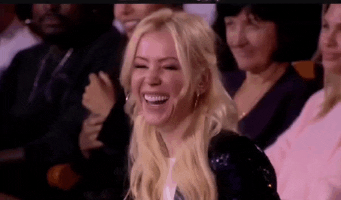 a woman is laughing while sitting in a crowd .
